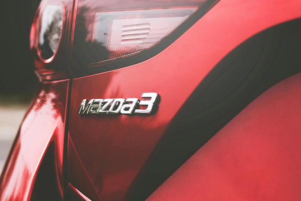 Close-up of Mazda 3 badge on red Mazda vehicle