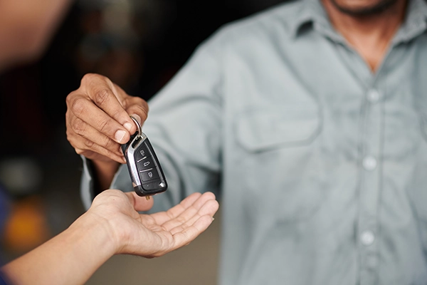 Man handing keys to buyer of vehicle during transaction