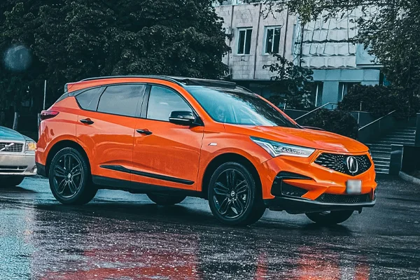 orange acura parked in the street